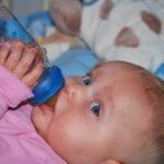 When should a baby start holding their bottle