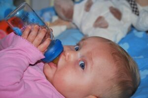 When should a baby start holding their bottle